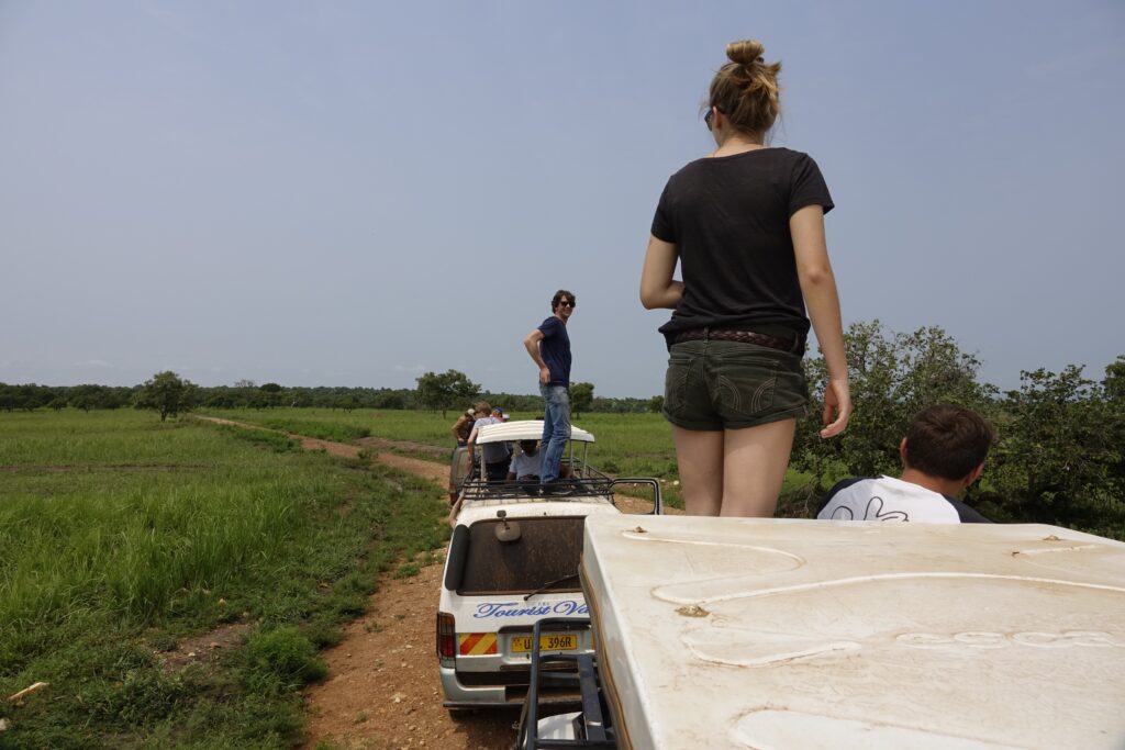 a group of people standing on top of a safari vehicle